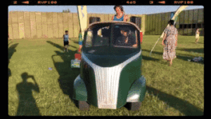 vintage golfkar rijdend op gras in een fort, tussen de mensen door