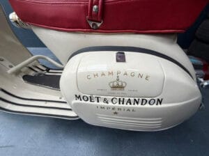 Zijkant van een Vespa oldtimer scooter met branding van een Champagne merk erop