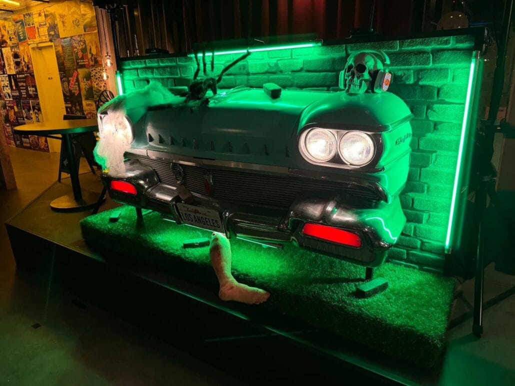 Een Oldsmobile uit de jaren 50 op een podium, verlicht en opgetuigd in het Halloween thema, als dj meubel