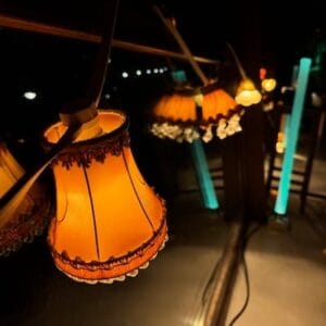 Sfeervol priklicht met oranje vintage lampenkapjes met franjes in een donkere omgeving.